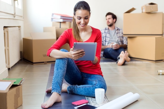 young couple with digital tablet resting in their new home